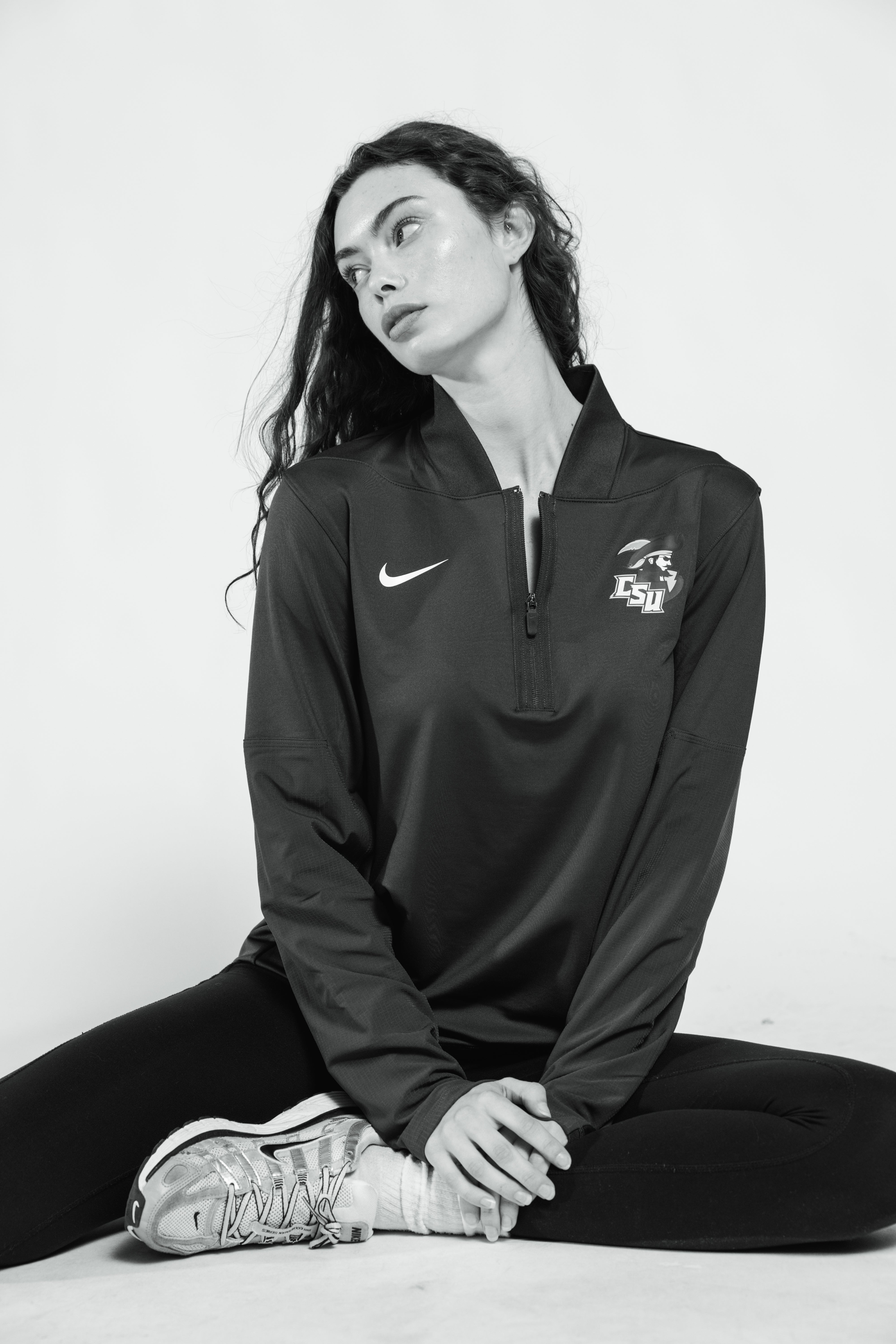Person wearing a black athletic jacket with   the charleston southern university and nike logo on a white background