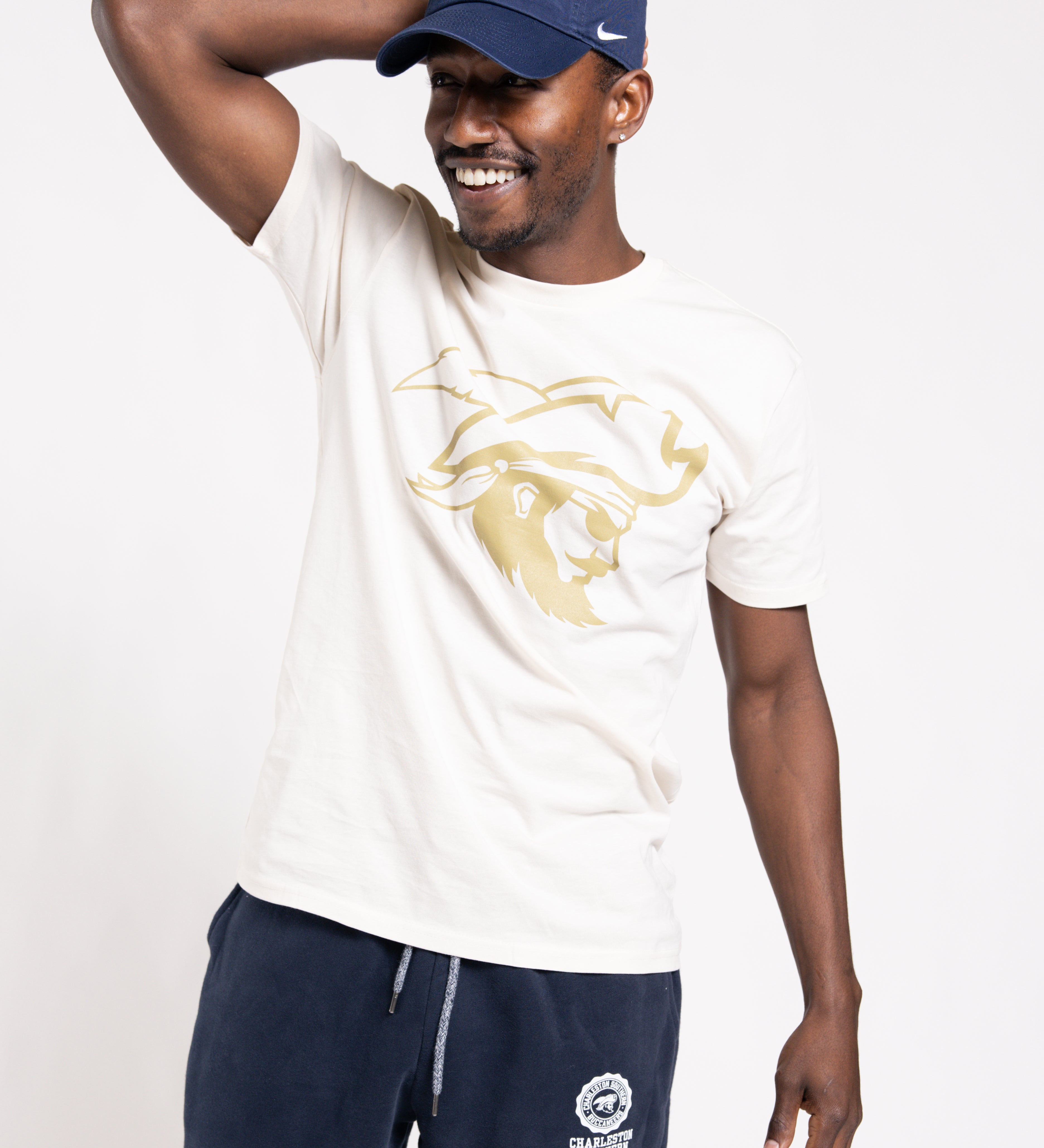 Man wearing a white t-shirt with a logo and navy pants, posing against a white background
