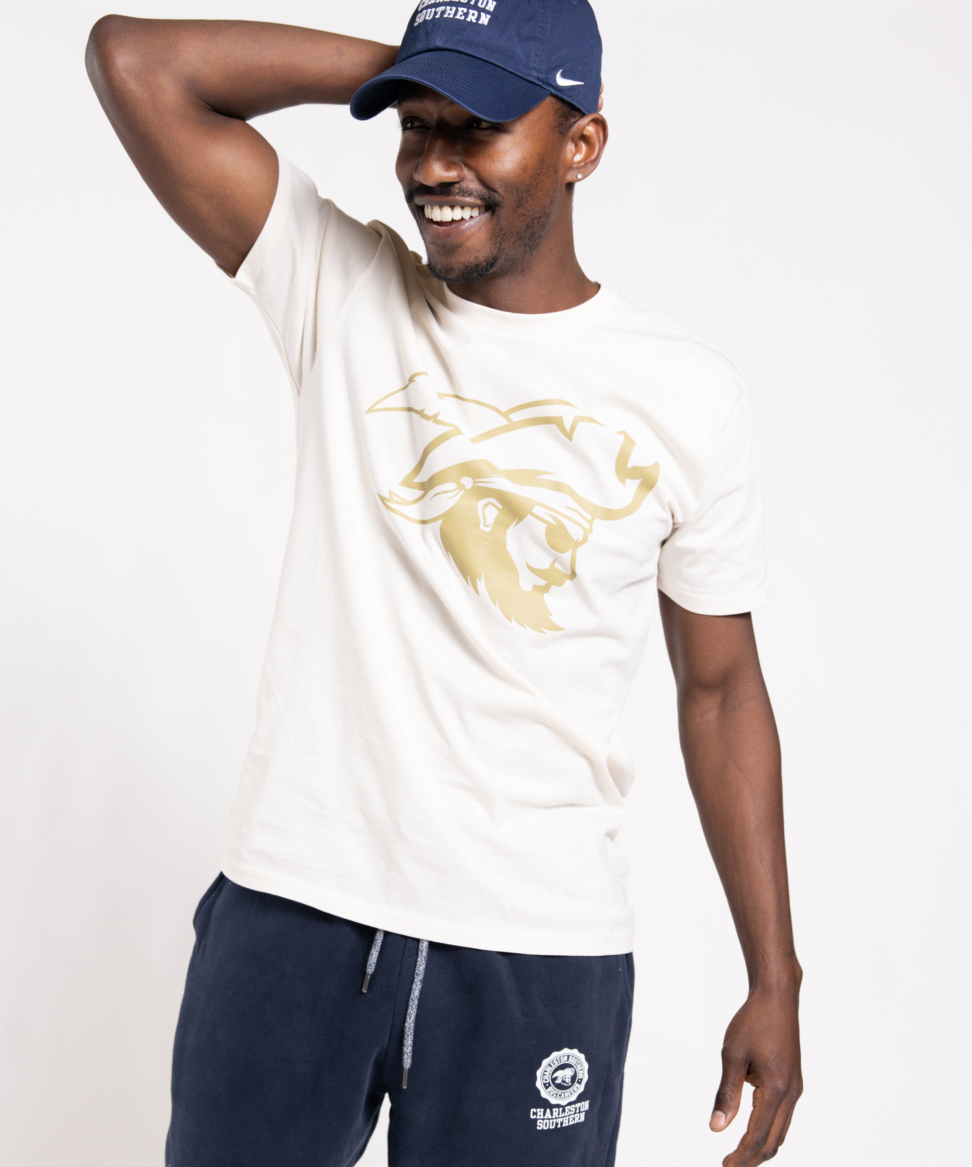 Man wearing a white t-shirt with a logo and navy pants, posing against a white background