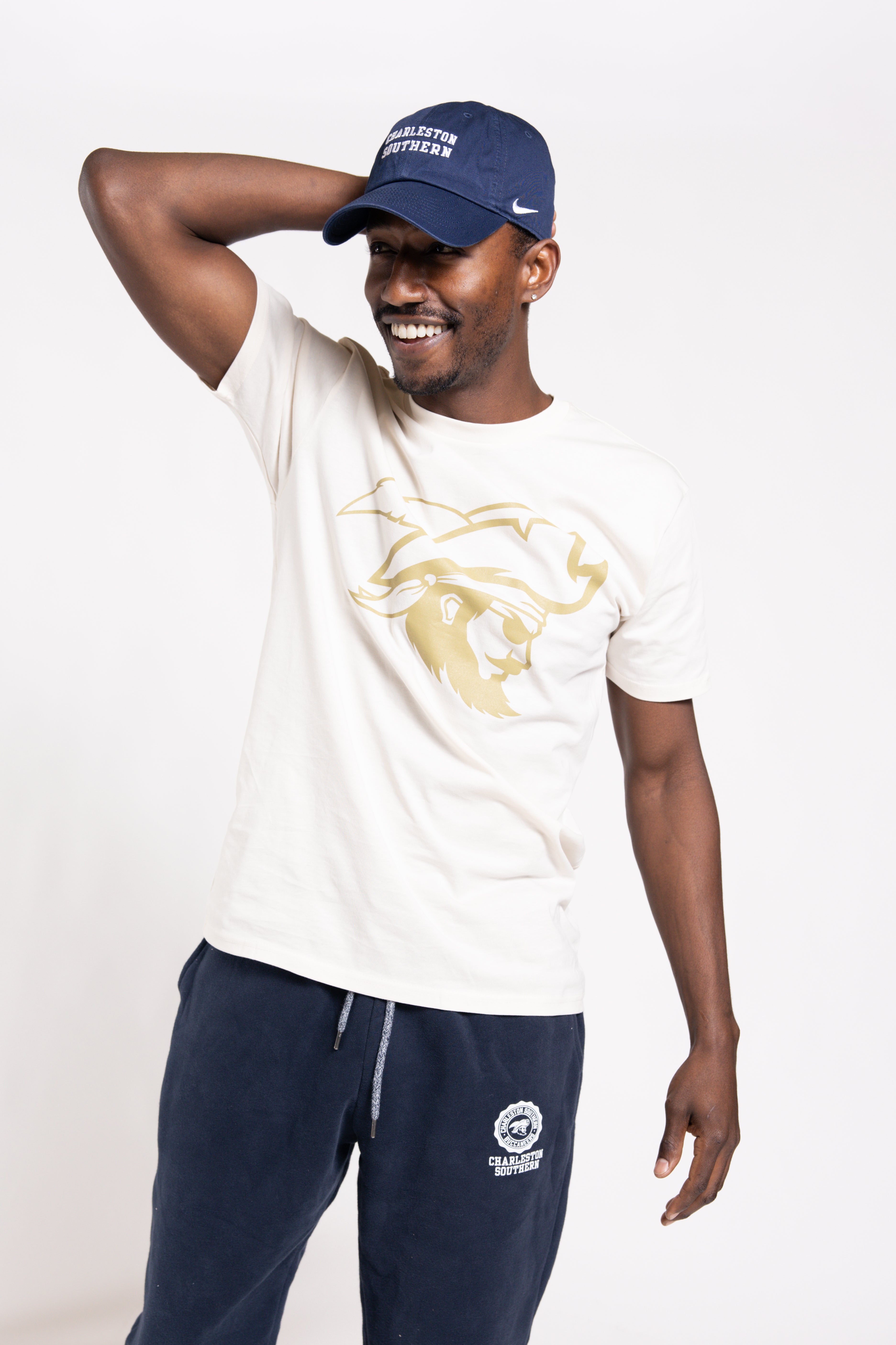 Man wearing a white t-shirt with a logo and navy pants, posing against a white background