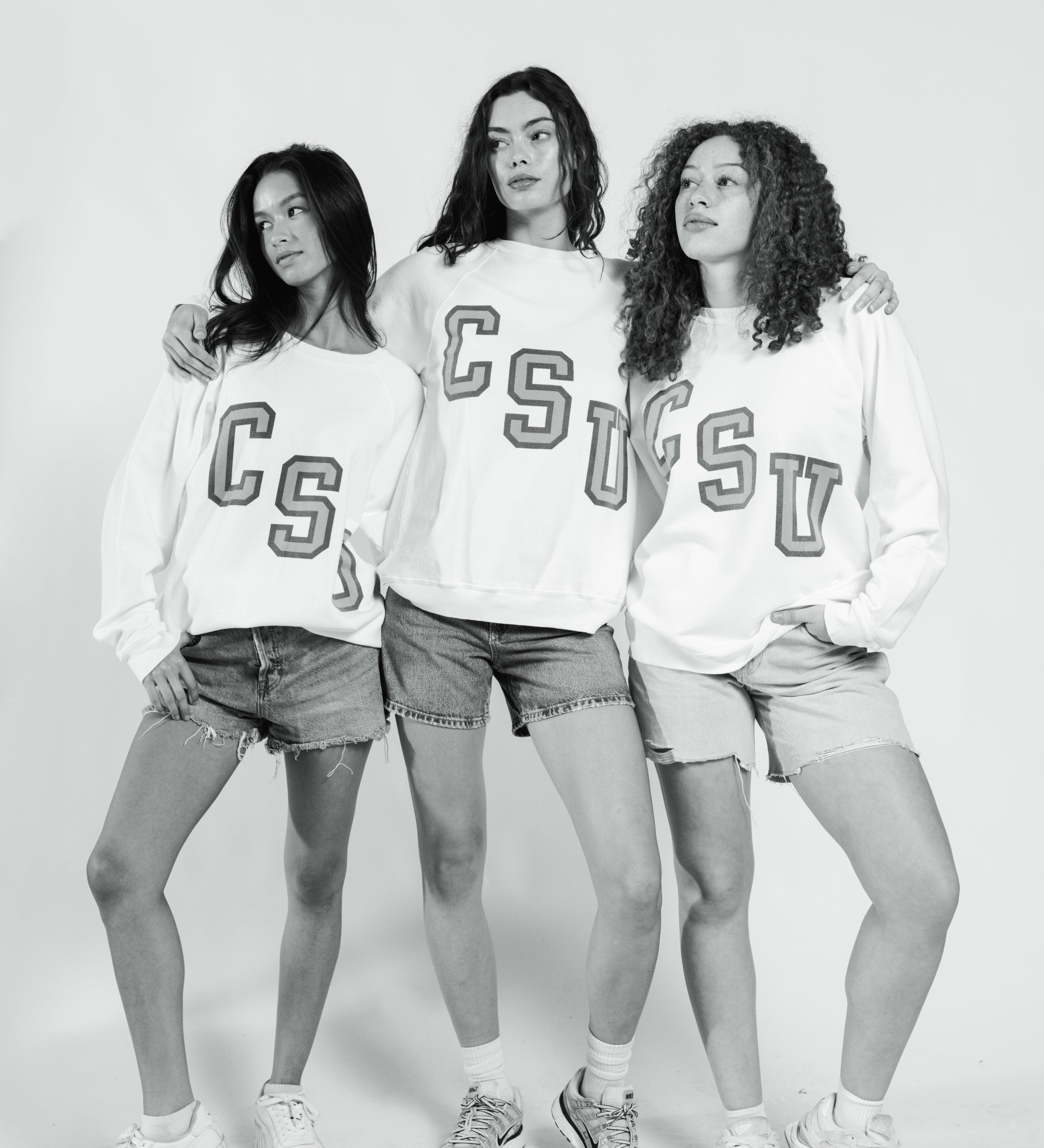 Three women wearing matching sweatshirts with 'CSU' on a white background